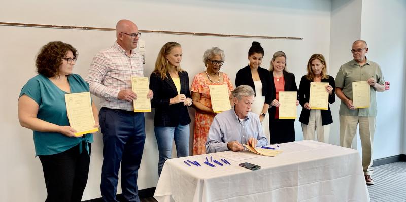 As Gov. John Carney signs one of seven housing bills, legislators, state officials and housing advocates look on. They are (l-r) Rachel Stucker, Housing Alliance Delaware executive director; Sen. Russ Huxtable, D-Lewes; Cynthia Karnai, Delaware State Housing Authority director; Rep. Stell Parker Selby, D-Milton; Sen. Elizabeth Lockman, D-Wilmington; Jennifer Smolko, deputy attorney general; Attorney General Kathy Jennings; and Rep. Ed Osienski, D-Newark. RON MACARTHUR PHOTO